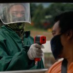 Un oficial de policía verifica la temperatura corporal de un pasajero en un punto de control de cuarentena en medio del estricto bloqueo reimpuesto para frenar las infecciones por COVID-19, en la ciudad de Quezon, Metro Manila, Filipinas,  REUTERS / Eloisa Lopez