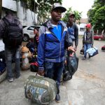 Emigrantes haitianos cargan sus pertenencias mientras tratan de resolver su situación legal para evitar ser deportados de Colombia y continuar su camino hacia Panamá y Estados Unidos, en Cali, REUTERS/Jaime Saldarriaga