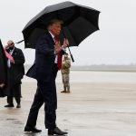 El presidente de Estados Unidos Donald Trump camina sin mascarilla y lleva un paraguas mientras sube al Air Force One al salir de Washington para viajar a Florida, su primer recorrido de campaña desde que fue tratado por la enfermedad coronavirus (COVID-19), en la Base Conjunta Andrews, Maryland, Estados Unidos. 12 de octubre de 2020. REUTERS/Jonathan Ernst