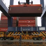 Una grúa carga un camión con un contenedor mientras los trabajadores supervisan la operación en el Puerto de Cartagena. REUTERS/Joaquín Sarmiento