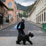 Un hombre con mascarilla pasea a su perro por una calle solitaria en uno de los barrios donde la alcaldía decretó cuarentena estricta, en medio de un brote de COVID-19, en Bogotá, REUTERS/Luisa Gonzalez/File Photo