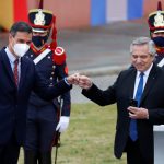 El presidente de Argentina, Alberto Fernández, mira su teléfono mientras choca el puño con el presidente del Gobierno de España, Pedro Sánchez, en el palacio presidencial de la Casa Rosada, en Buenos Aires. 9 de junio de 2021. REUTERS/Agustin Marcarian