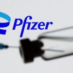 Una jeringa y un vial se ven frente al nuevo logo de Pfizer en esta ilustración tomada el 24 de junio de 2021 REUTERS/Dado Ruvic