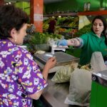 Una mujer recibe su cambio de una cajera en un supermercado en Bogotá, REUTERS/Luisa González