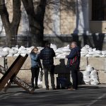 Un grupo de personas toma café mientras conversa este jueves ante los bloques de hormigón que cierran el paso a una de las avenidas de la ciudad de Odesa. EFE/Manuel Bruque