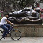 Un hombre cruza en bicicleta frente a una escultura del artista colombiano Fernando Botero, el 17 de abril de 2022, en la Plaza Botero, en Medellín. EFE/ Luis Eduardo Noriega A.