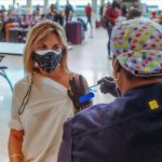 Persona recibe vacuna utilizando tapaboca en EE.UU Foto The New York Times