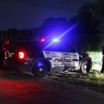 Policías y funcionarios bloquean cerca de un camión con remolque al costado de la vía que conduce al lugar donde habrían sido encontrados muertos más de al menos 51 migrantes y al menos 15 que todavía estaban vivos, en una carretera cerca de las vías del tren en San Antonio, Texas, EE. UU., 28 de junio de 2022. (Estados Unidos) EFE/EPA/ADAM DAVIS