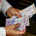Hombre cuenta billetes colombianos