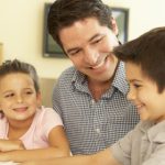 Hispanic Father And Children Using Computer At Home